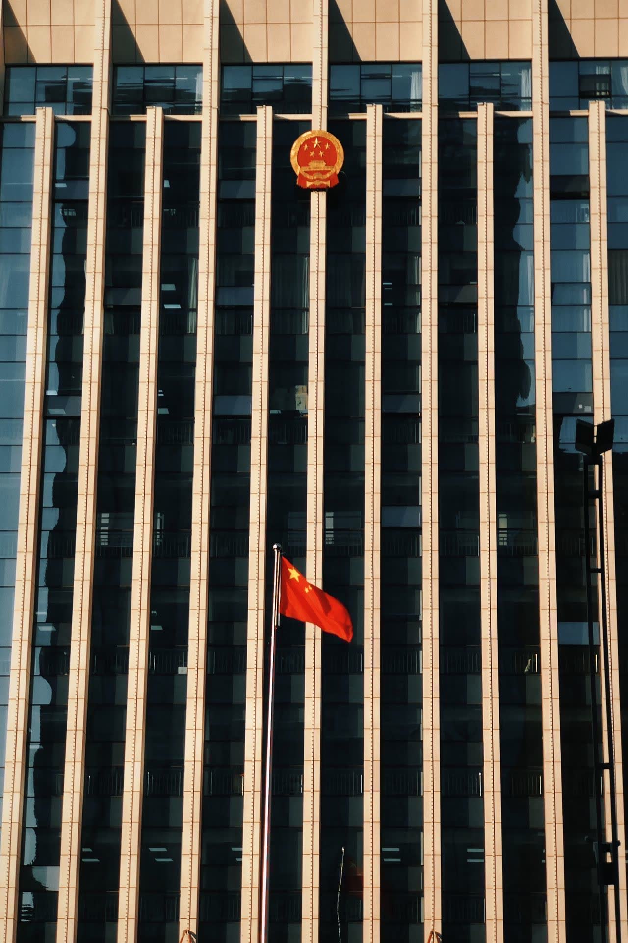 A Chinese data centre building with security barriers and government seals, overcast sky, photojournalistic style