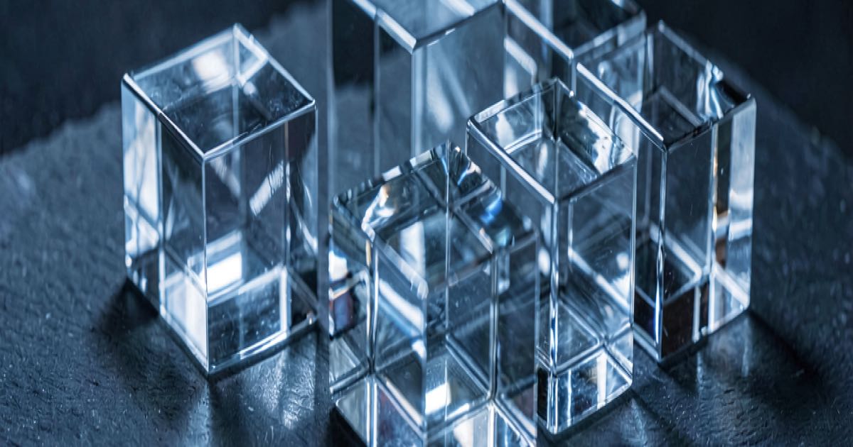 Translucent glass cubes on a dark slate surface with cool blue light refraction, minimalist tech editorial still life.