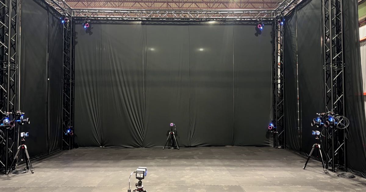 Infrared motion-capture cameras on tripods and rigging surround a black curtained capture stage at Innodata's new physical-AI lab