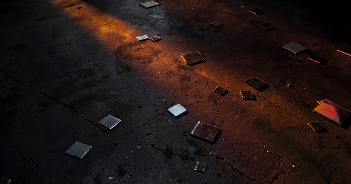 Abstract composition of semiconductor wafers on dark concrete reflecting orange and red light in a moody industrial atmosphere